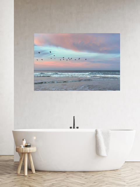 Canvas print of birds flying over pastel pink sunrise in Morro Bay over a bathtub in a bathroom