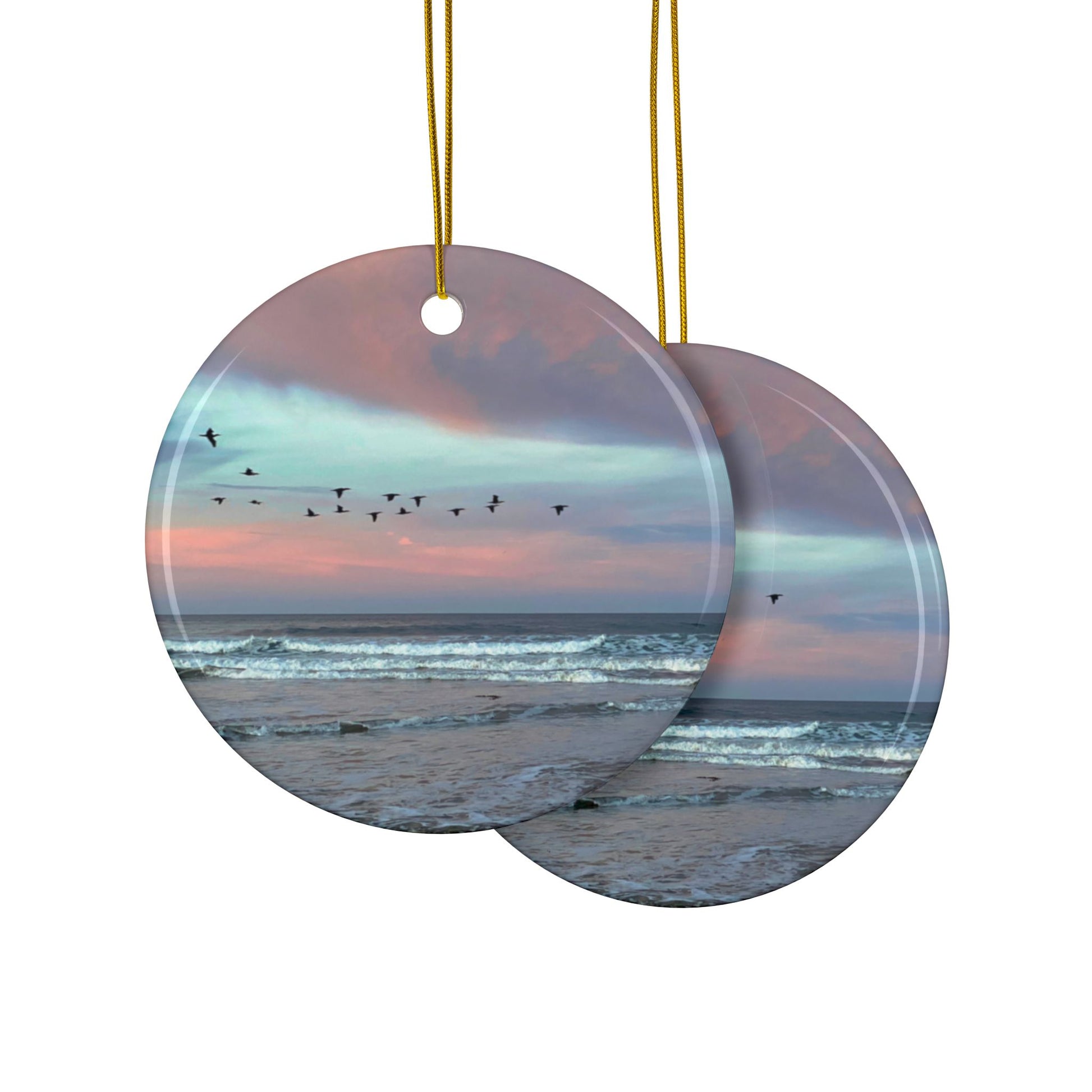 Front and back side of a ceramic holiday ornament featuring a photograph of a flock of birds flying across a pastel pink and violet sunrise sky over the Pacific ocean.