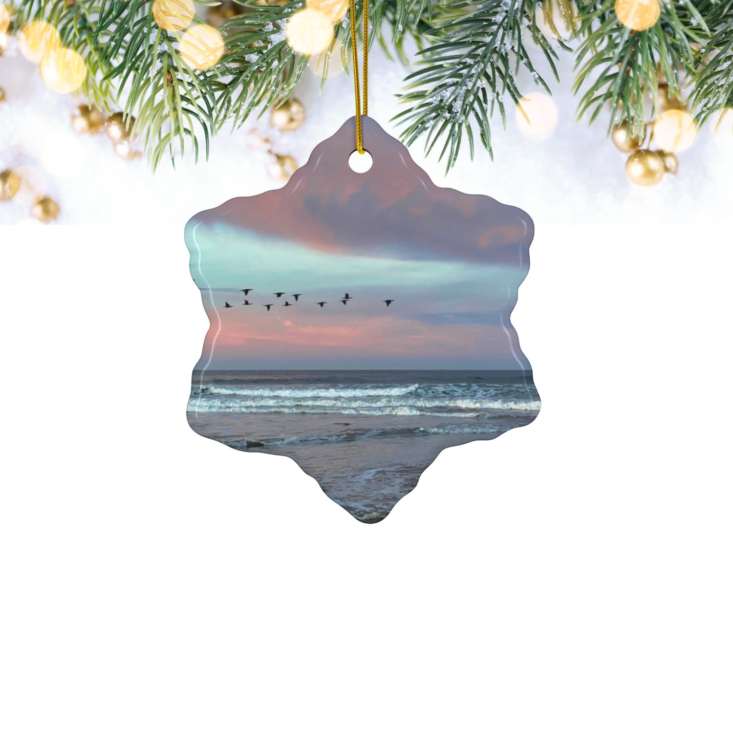 Ceramic holiday ornament featuring a photograph of a flock of birds flying across a pastel pink and violet sunrise sky over the Pacific ocean hanging against a white background