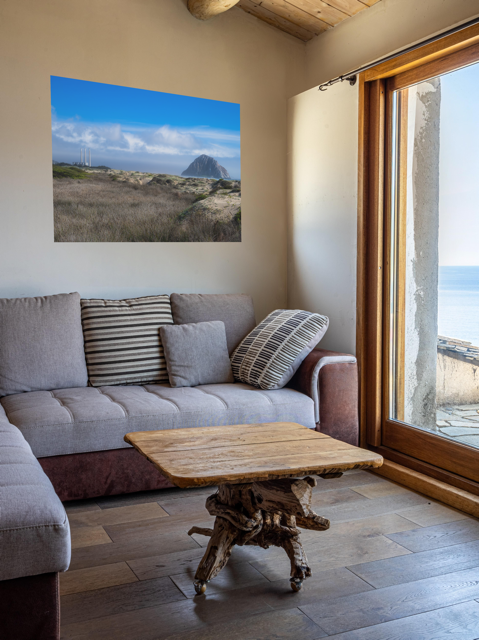 Living room with a gray sofa, wooden coffee table, and a Morro Rock and stacks view from the beach dunes canvas print.