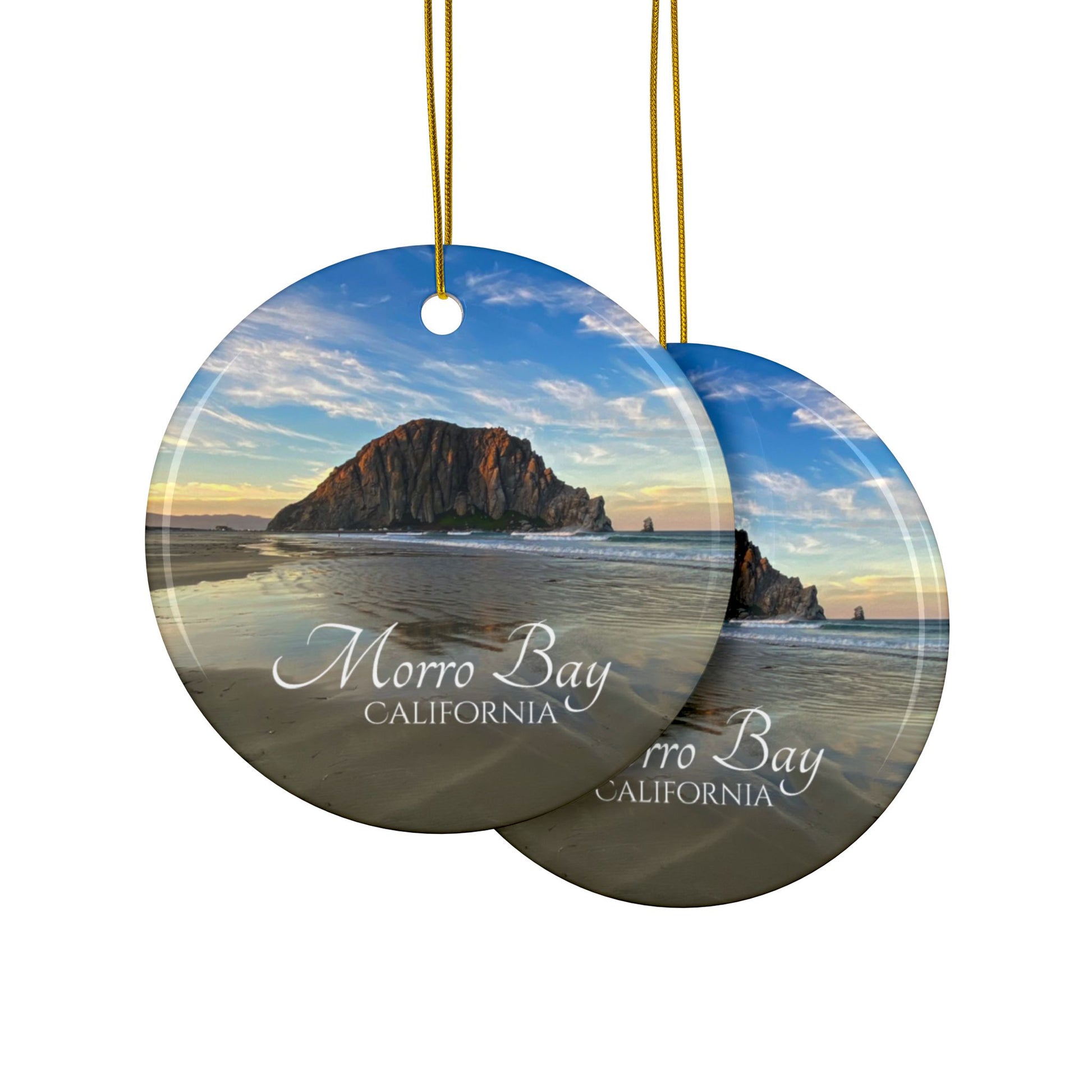 Front and back side of a ceramic holiday ornament featuring a photograph of Morro Rock in Morro Bay, California, with reflections in the sand under a dramatic afternoon sky.