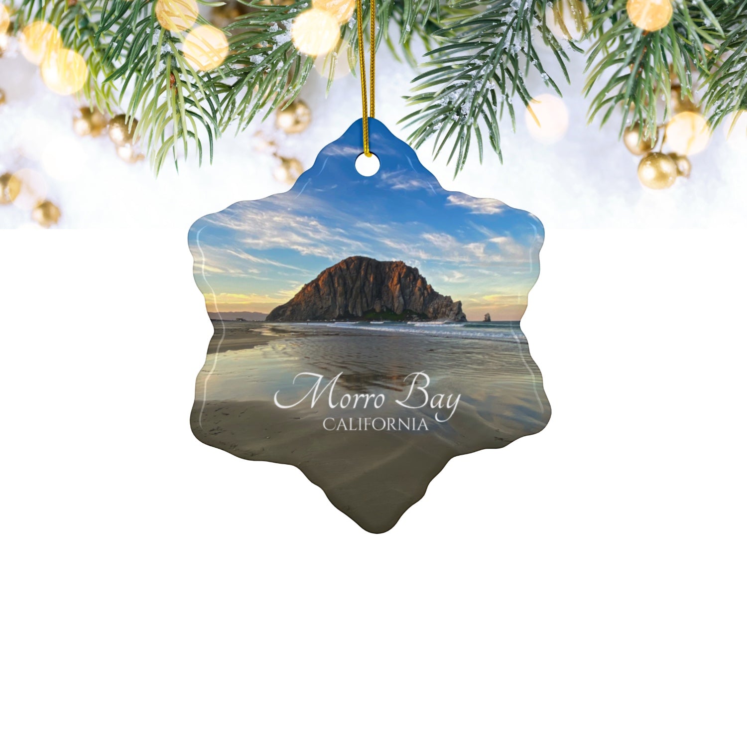 Ceramic holiday ornament featuring a photograph of Morro Rock in Morro Bay, California, with reflections in the sand under a dramatic afternoon sky.