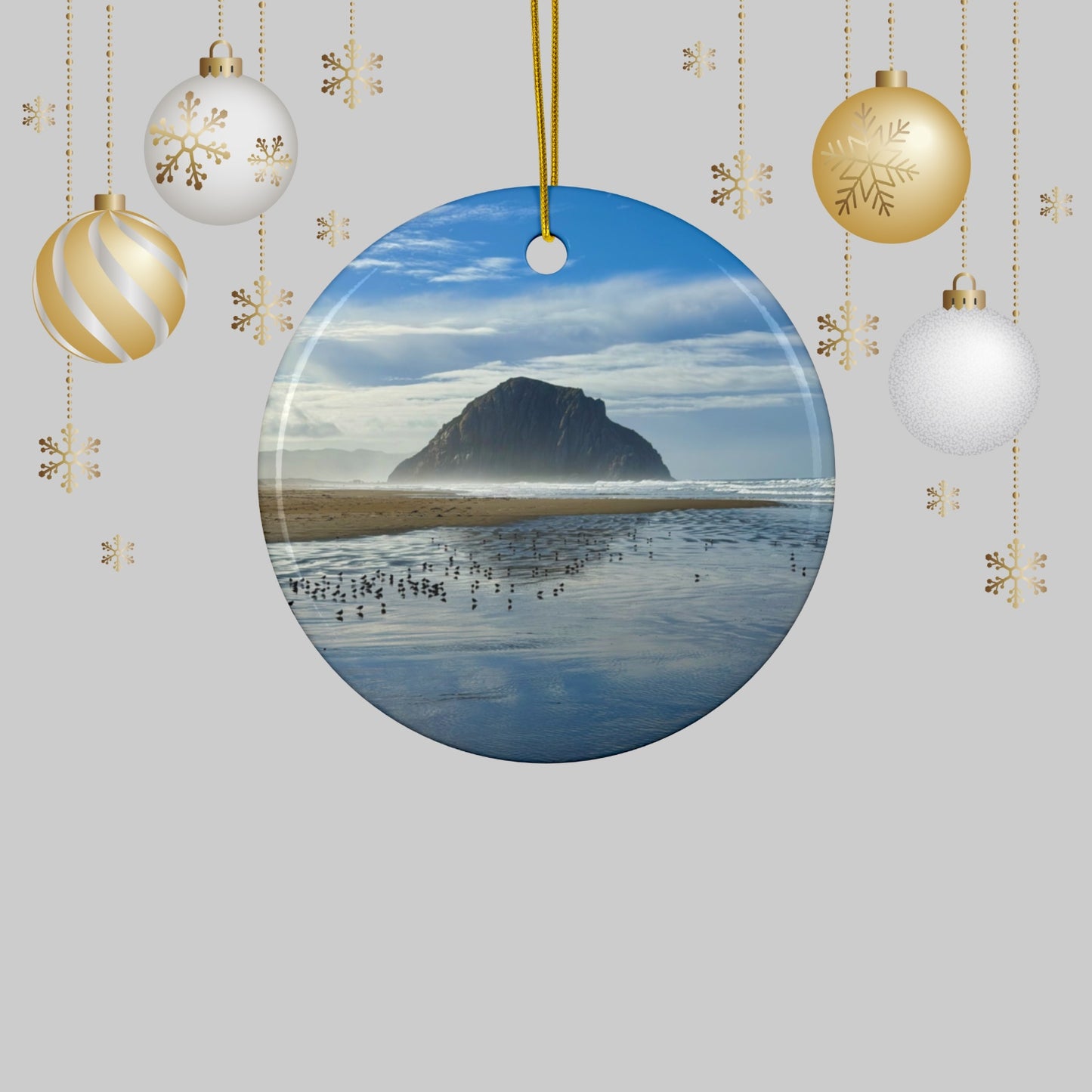 Ceramic holiday ornament featuring a professional photograph of Morro Rock in Morro Bay, California, with the Pacific surf in the foreground, surrounded by Christmas ornaments on a light gray background