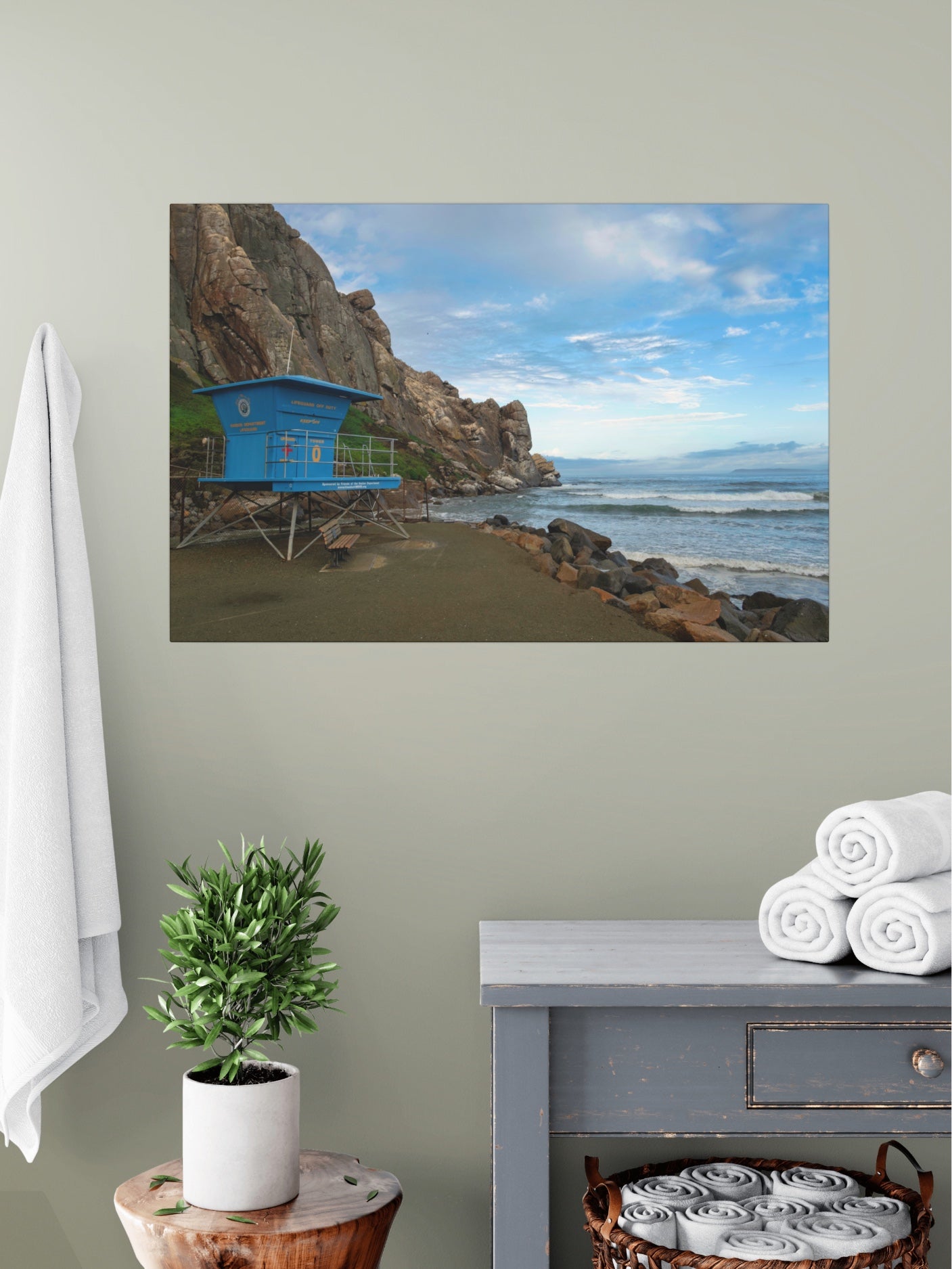 Blue lifeguard tower at the base of Morro Rock in Morro Bay California canvas print on wall above vanity with towels and plant