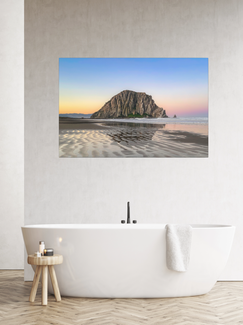 Canvas print featuring a Morro Rock morning reflection in wet beach sand on a wall above a white bathtub.