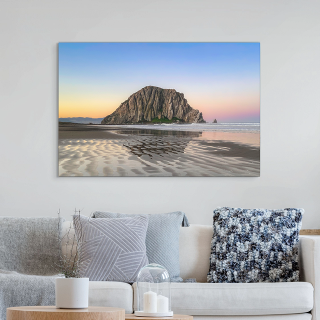 canvas print featuring a Morro Rock morning reflection in wet beach sand on a wall above a living room sofa.