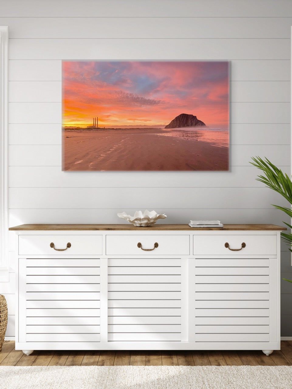A canvas print of Morro Rock and the stacks at sunrise above a white cabinet with wooden top