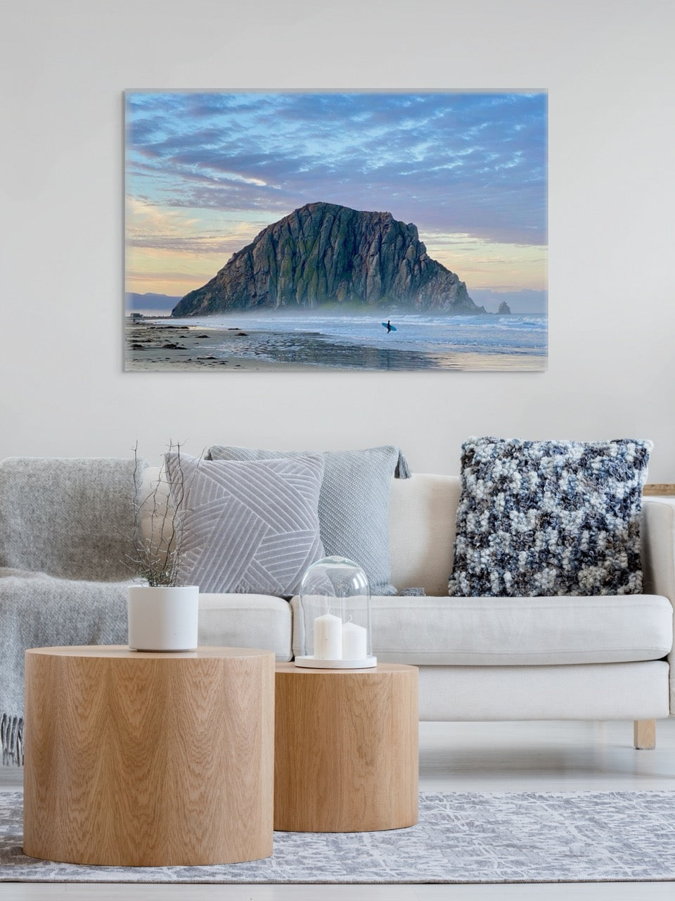 Canvas print of a sunrise at Morro Rock in Morro Bay, California with a surfer on the beach in a living room with a couch, coffee table.