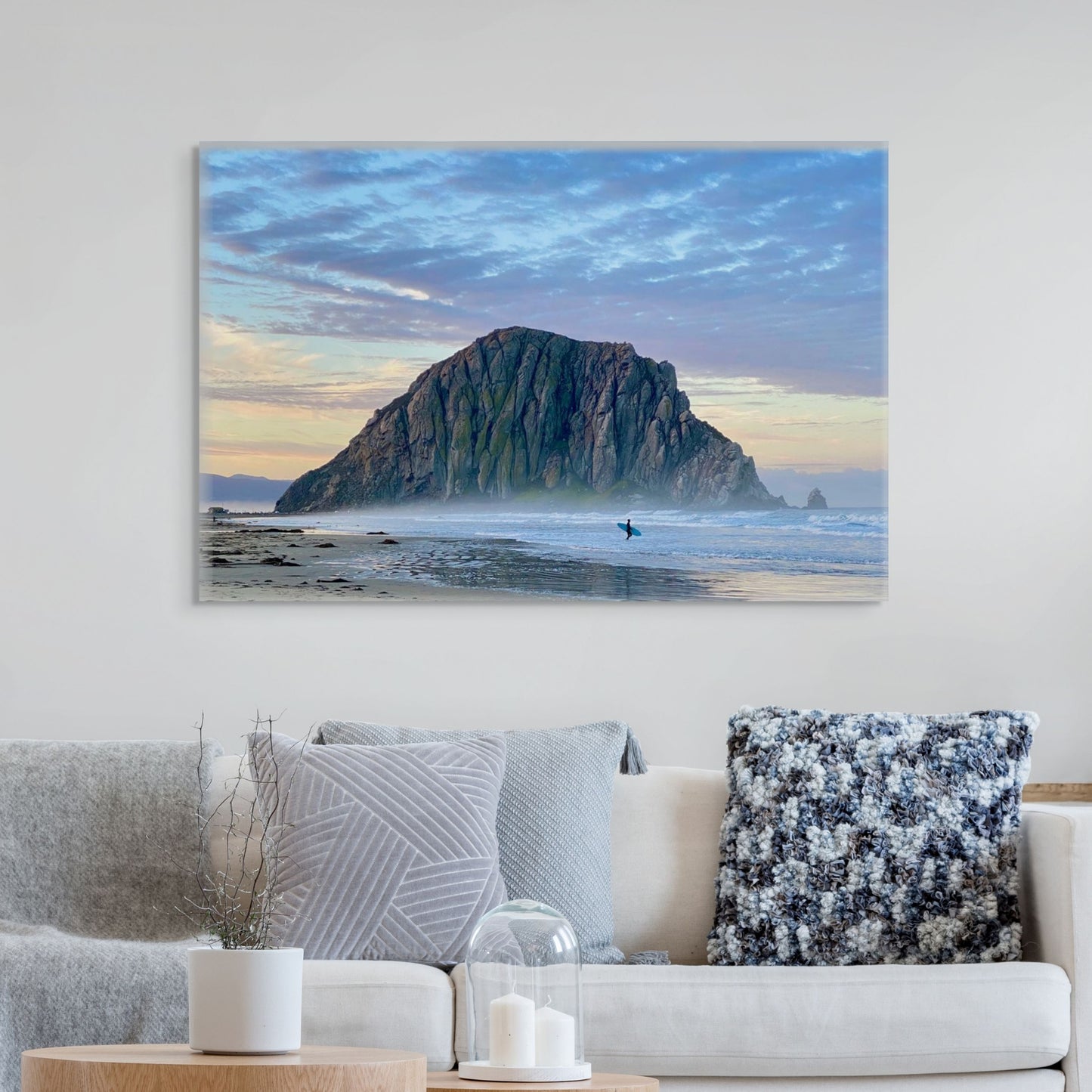 Canvas print of a sunrise at Morro Rock in Morro Bay, California with a surfer on the beach hanging above a living room sofa.