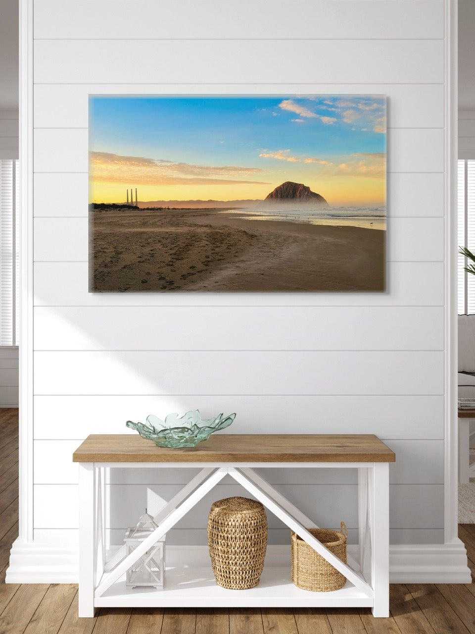 Canvas print of Morro Rock and the stack at sunrise on a wall above a wooden bench with storage.
