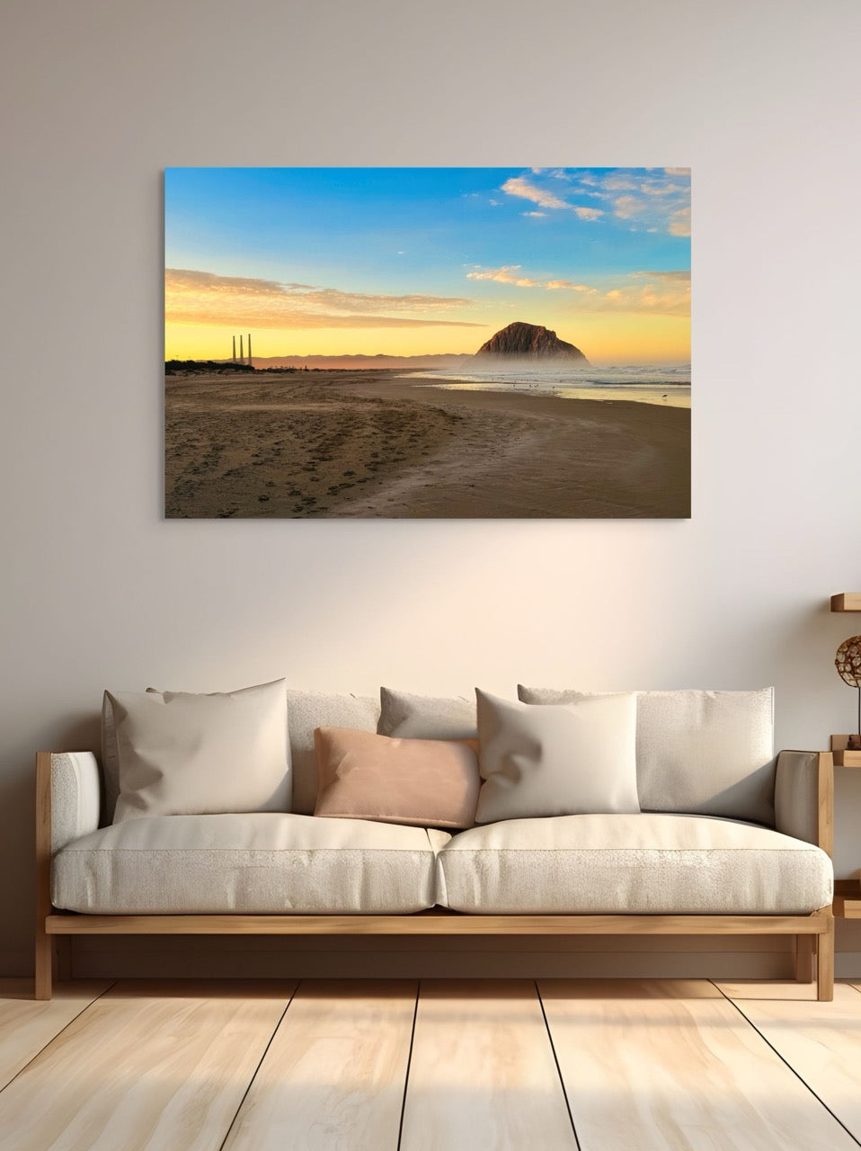 Canvas print of Morro Rock and the stack at sunrise on a wall above a sofa with cushions.