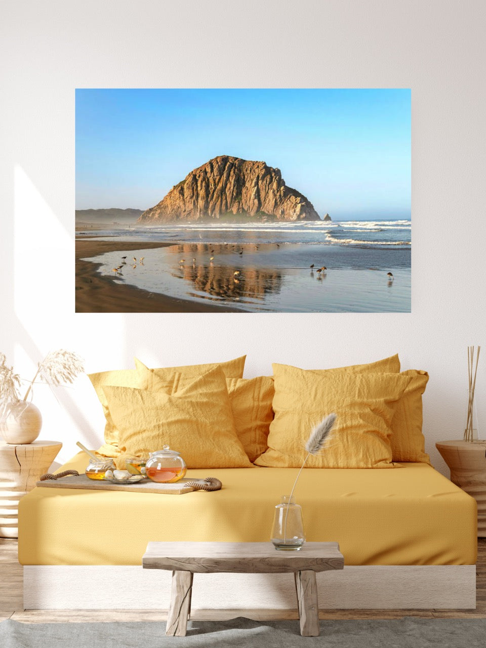 Canvas print of Morro Rock reflecting in the wet sand with birds on the shoreline. on a wall above a yellow couch.
