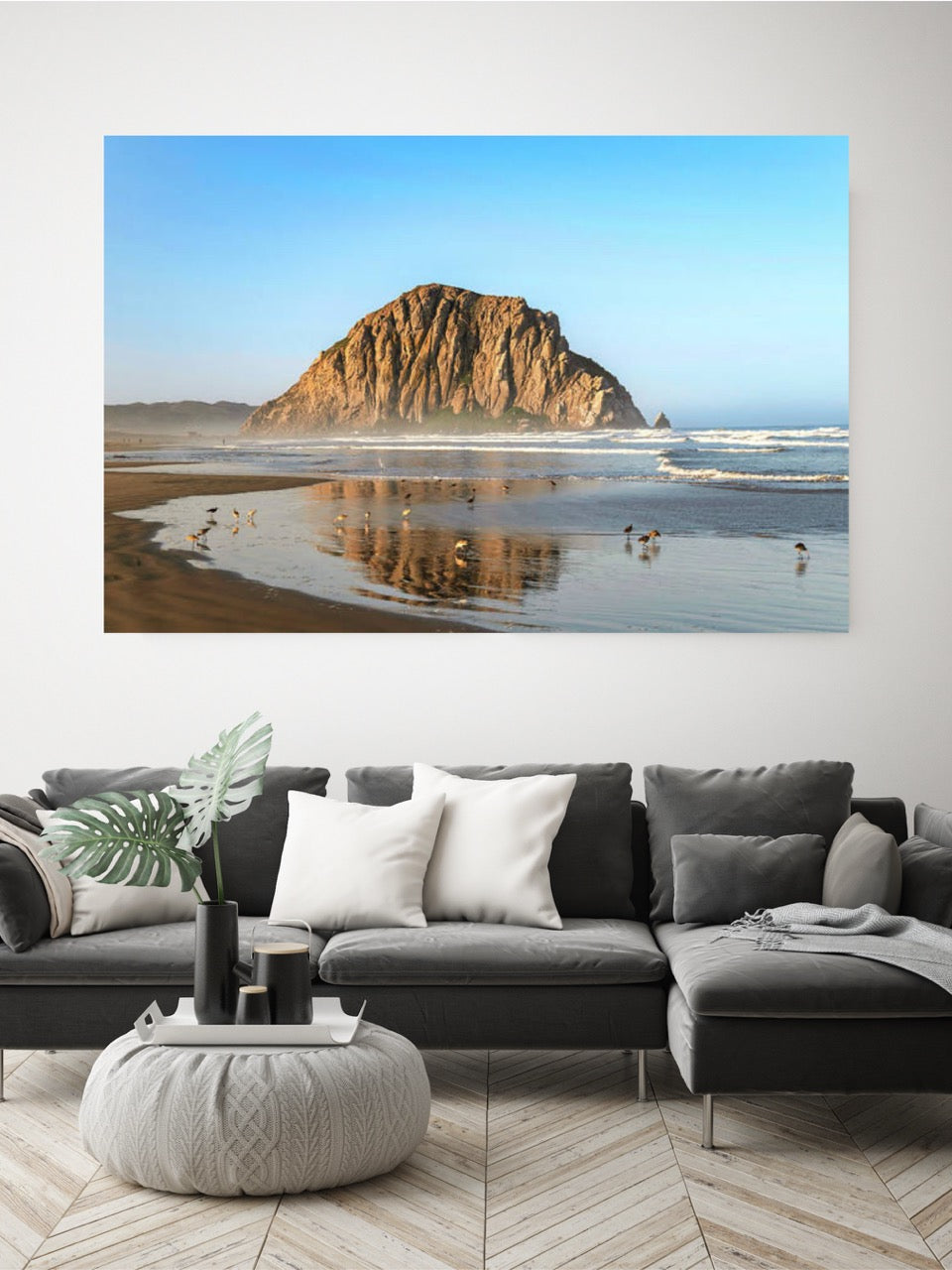 Beach scene with Morro Rock on a wall above a gray sectional sofa.