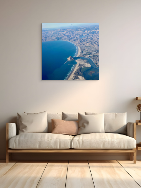 Sofa with decorative pillows in a room with an aerial photography of Morro Rock and California coastline canvas print