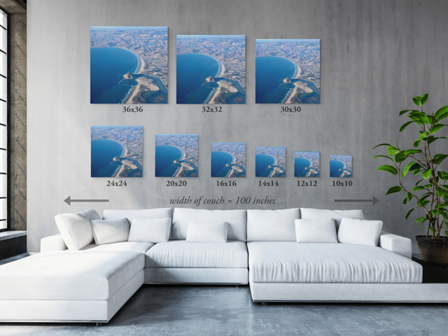Wall art prints of the same coastal scene arranged above a white sectional sofa.