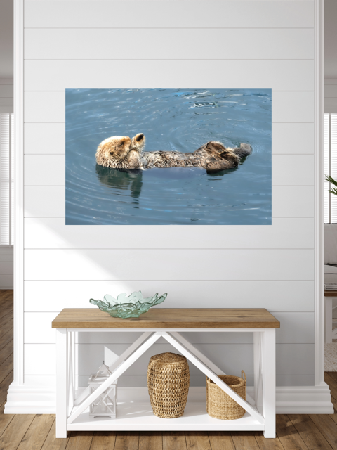 Canvas print of a sea otter in water on a wall above a wooden bench with storage baskets.