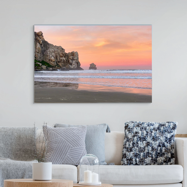 Beach scene canvas print on a wall above a sofa with decorative pillows.