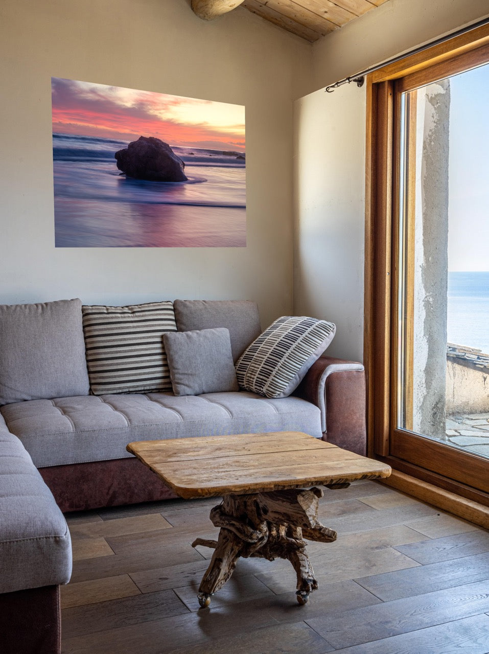 Living room with a gray sofa, wooden coffee table, and a canvas print of a large ocean rock on the wall.