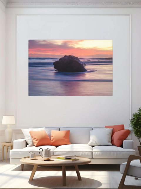 Living room with a canvas print of a large ocean rock above a white sofa with colorful cushions.