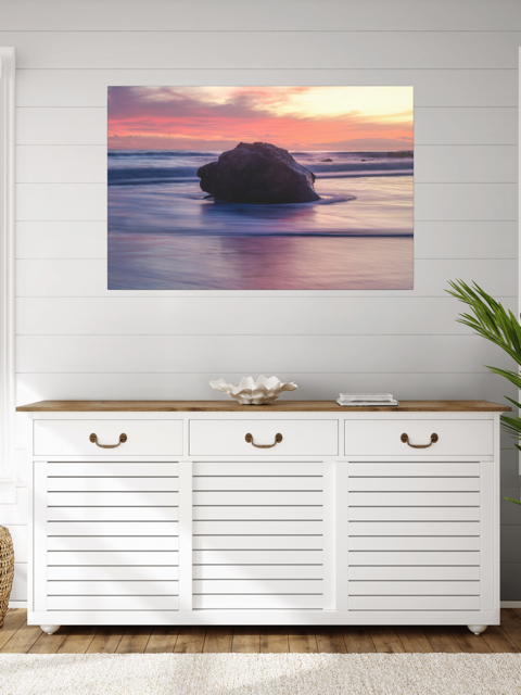 White cabinet with wooden top against a wall with a a canvas print of a large ocean rock.