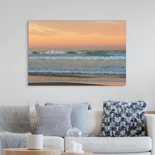 Canvas print of a sunrise sky over ocean waves above a sofa in a living room