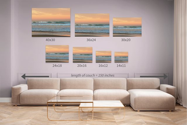 Wall art prints of ocean waves at sunrise displayed above a sofa with measurements shown