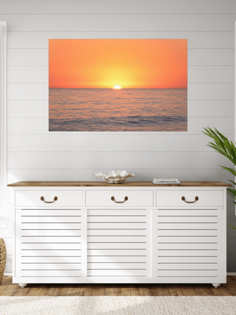 White cabinet with wooden top in a room with a canvas print of a sunset over the ocean on the wall.