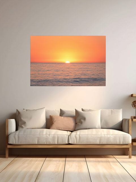 A canvas print of a sunset over the ocean on he wall over a beige sofa.