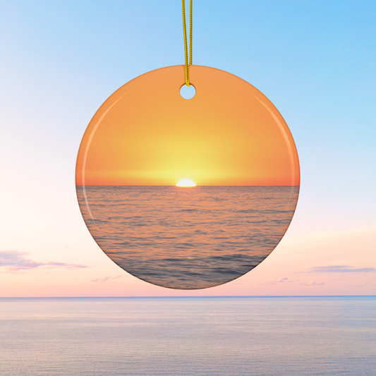 Ceramic Christmas ornament featuring a minimalist photograph of a vibrant orange and amber sunset sky over a calm Pacific Ocean on a clear blue sky background