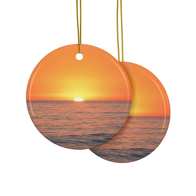 Front and back sides of a ceramic Christmas ornament featuring a minimalist photograph of a vibrant orange and amber sunset sky over a calm Pacific Ocean