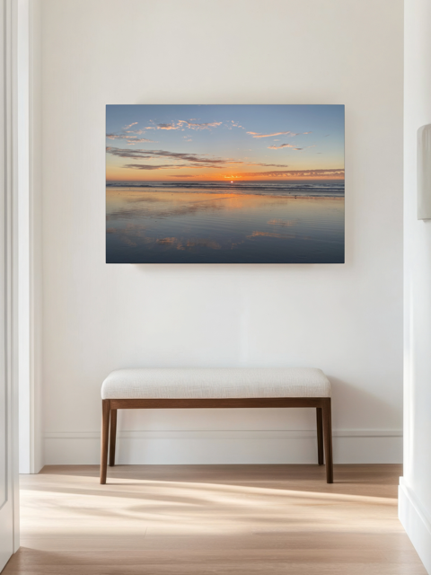 Pacific Ocean sunset reflection on beach during King Tide canvas print on a wall in a room with a bench.