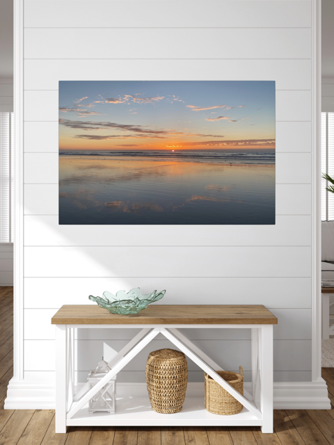 Pacific Ocean sunset reflection on beach during King Tide canvas print on a wall in a room with a wooden bench and decorative items.