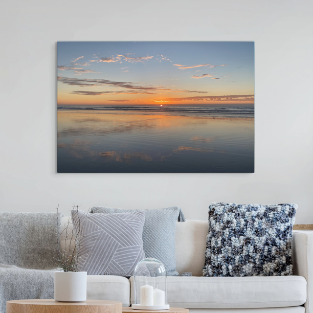 Pacific Ocean sunset reflection on beach during King Tide canvas print hanging above a living room sofa.