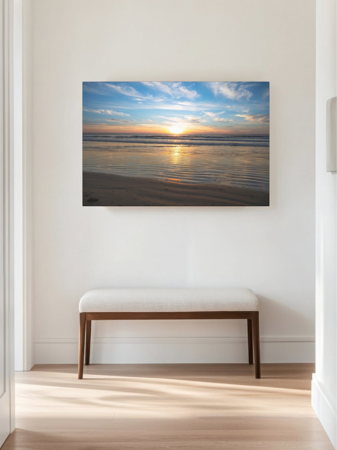 California beach sunset over the ocean with golden sand ripples canvas print on a wall above a bench in a room.