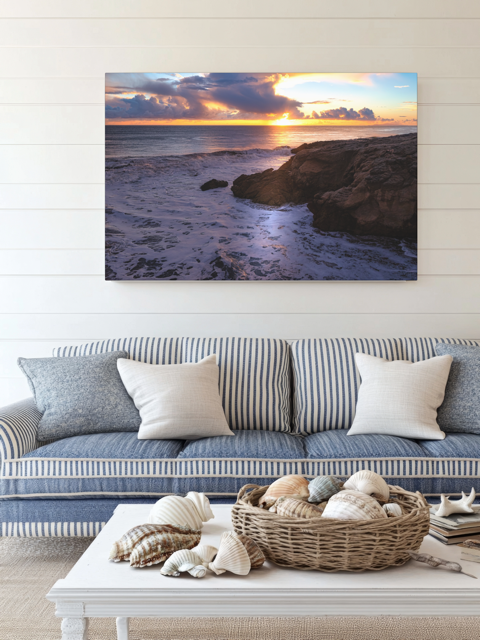 Living room with a couch, coffee table, and a California coastal sunset after rain storm canvas print.