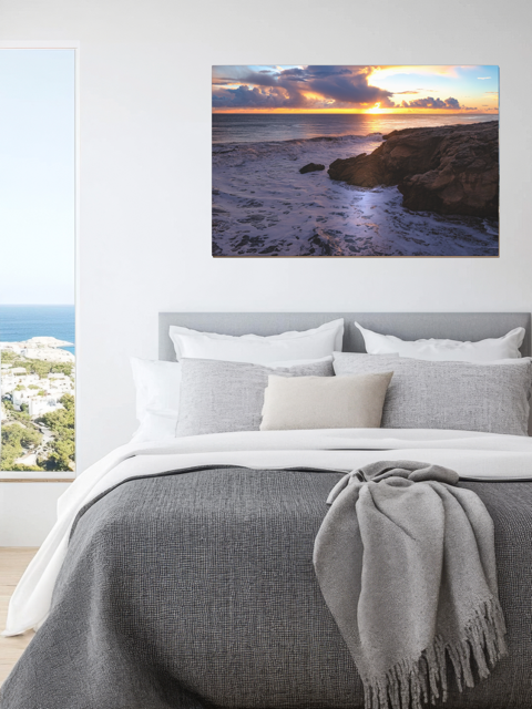 Bedroom with a California coastal sunset after rain storm canvas print above the bed.