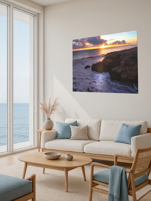 Living room with a large window view of the ocean, a beige sofa with blue cushions, and a California coastal sunset after rain storm canvas print.
