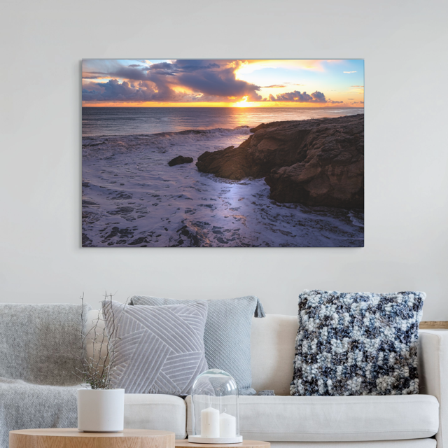 California coastal sunset after rain storm canvas print hanging above a living room sofa.