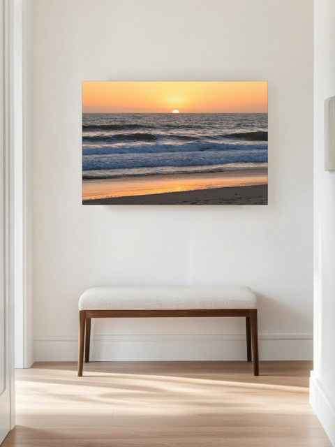 Pacific Ocean sunset and waves on beach canvas print on a wall above a bench