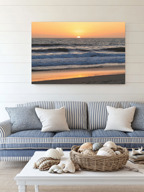 Living room with a couch, coffee table, and a Pacific Ocean sunset and waves on beach canvas print on the wall.