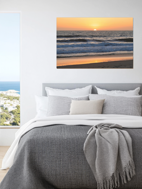Bedroom with a lPacific Ocean sunset and waves on beach canvas print above the bed.