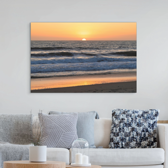 Pacific Ocean sunset and waves on beach canvas print on wall above sofa with decorative pillows