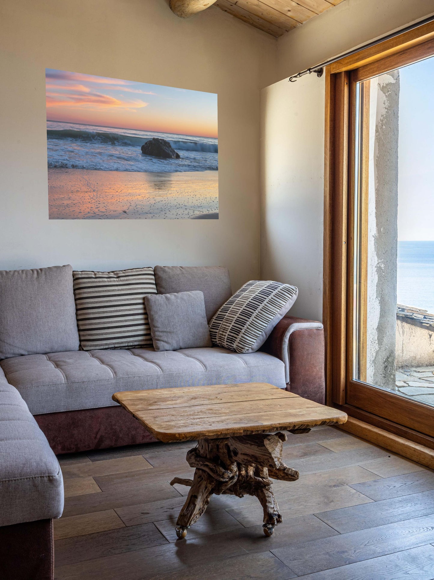 Living room with a gray sofa, wooden coffee table, and a pastel beach twilight canvas print with pink clouds reflecting on wet sand.