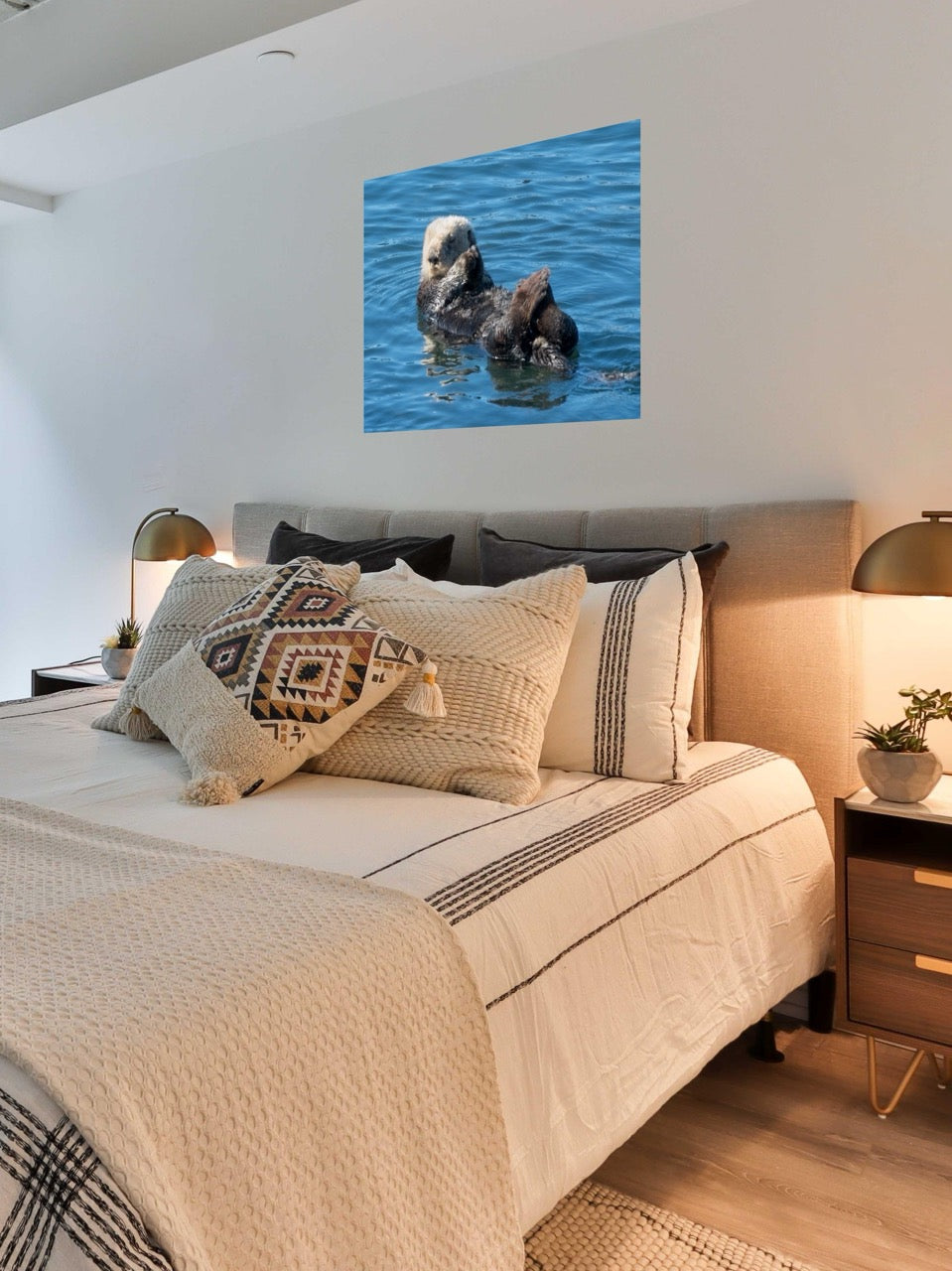 Bedroom with a bed featuring patterned pillows and a wall art of a sea otter in water.