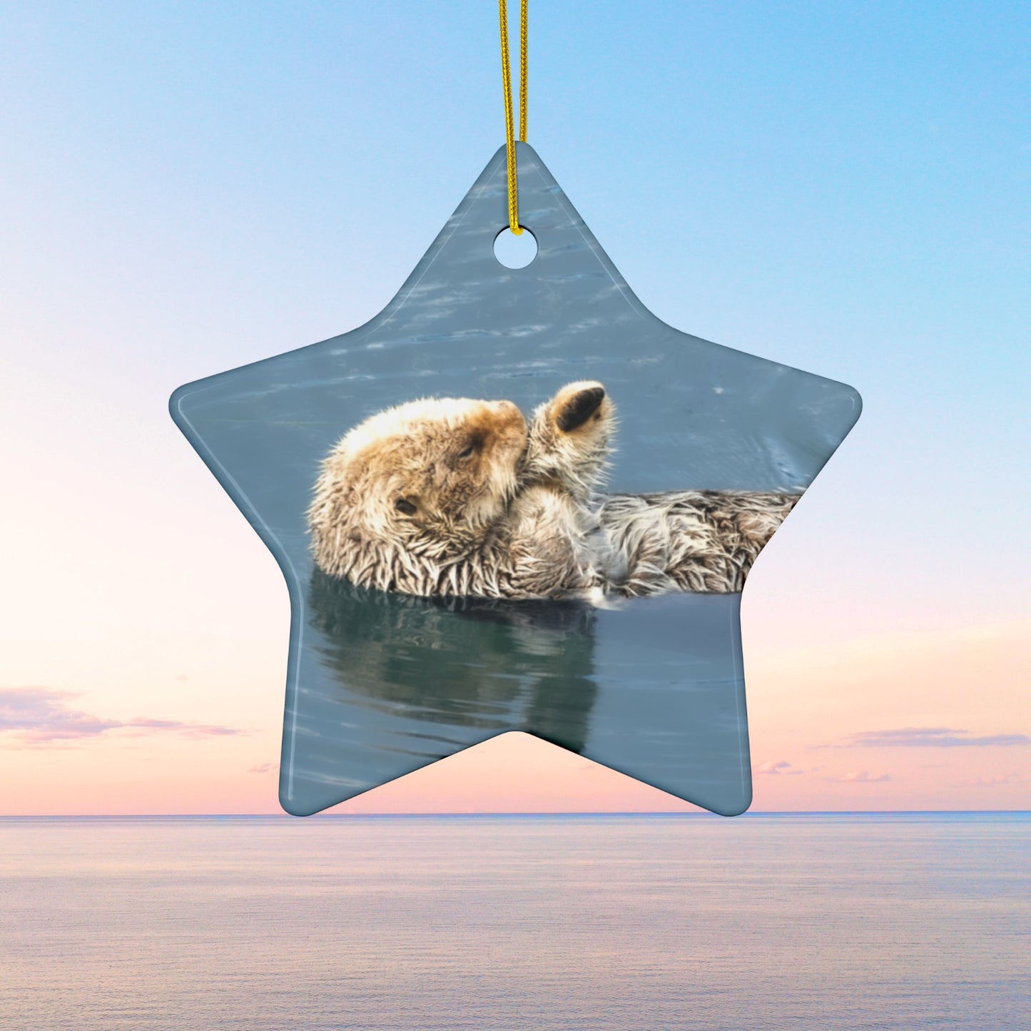 Star-shaped ornament featuring a professional photograph of a sea otter floating on its back in the blue waters of the Pacific Ocean