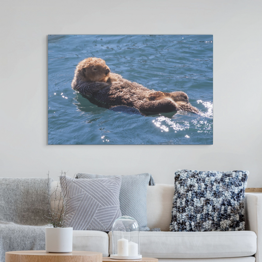 Canvas print of an otter in water hanging on a wall above a sofa.
