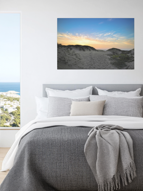 Bedroom with a canvas print of a beach sunset over the sand dunes above the bed.