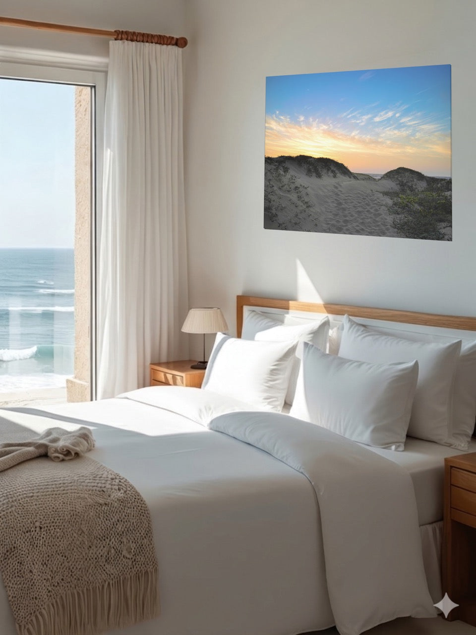 Bedroom with a large bed, ocean view, and a canvas print of a beach sunset over the sand dunes on the wall.