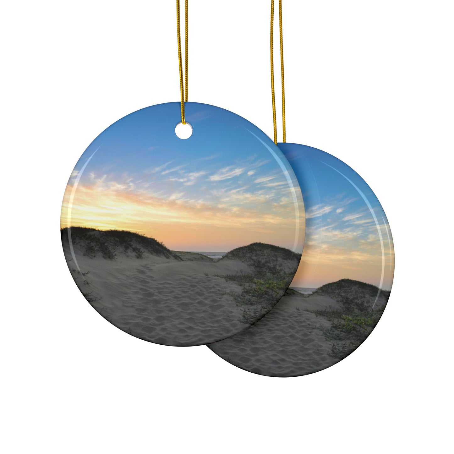 Front and back side of a ceramic holiday ornament featuring a landscape photograph of a California beach at sunset with rolling sand dunes, footprints, and gold-streaked clouds.