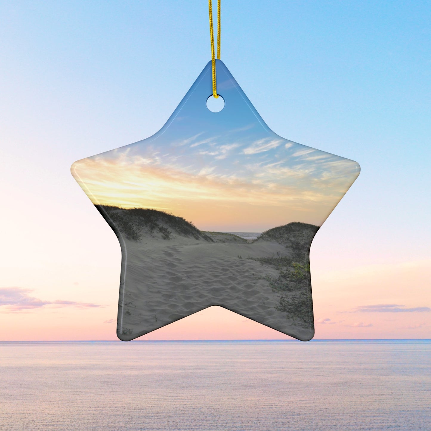 Star-shaped ceramic holiday ornament featuring a landscape photograph of a California beach at sunset with rolling sand dunes, footprints, and gold-streaked clouds.